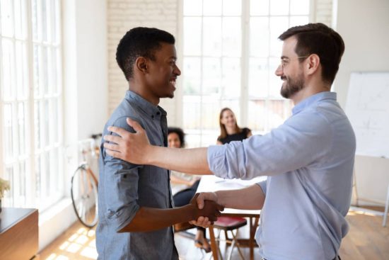Dos hombres sonrientes mirándose a la cara y dándose ánimo.