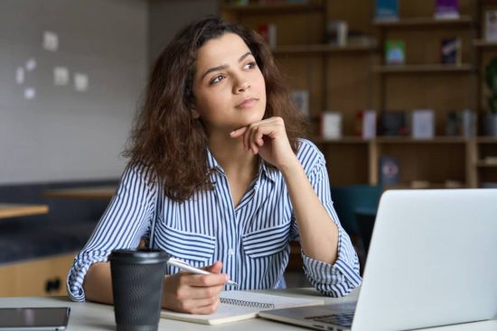 Qué es el autoconocimiento. Mujer observando hacia el horizonte y anotando en un cuerderno.