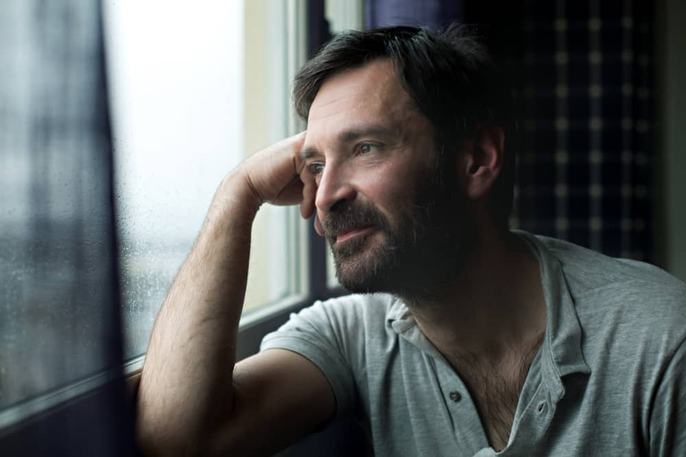 Qué es el autoconocimiento. Hombre sonriente mirando hacia la ventana.