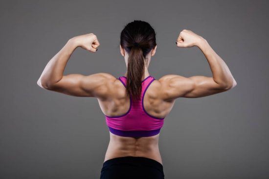 Espalda de mujer fitness haciendo flexión muscular con mucha luz, remo gironda