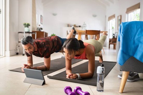Un hombre y una mujer realizan entrenamiento online en casa.