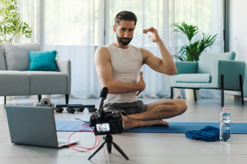 Hombre joven realiza un entrenamiento online frente a las cámaras en su casa